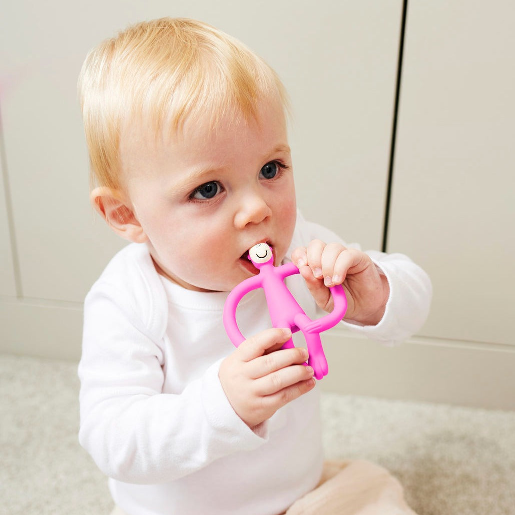Bright Pink Silicone Monkey Teething Toy with baby holding it in its mouth.
