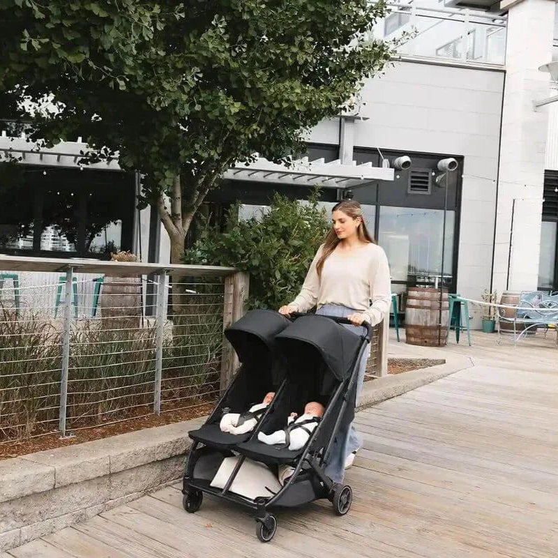 Woman pushing a UPPAbaby Minu Duo with two twin babies in it.