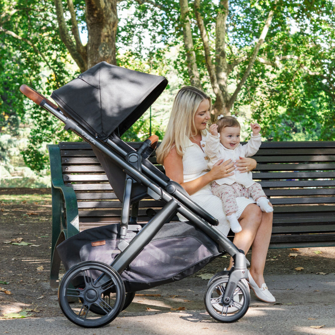 UPPAbaby Vista Nori Stroller (single) Black fabric, black carbon frame and Chestnut leather handle and bumper bar. Lifestyle Image.