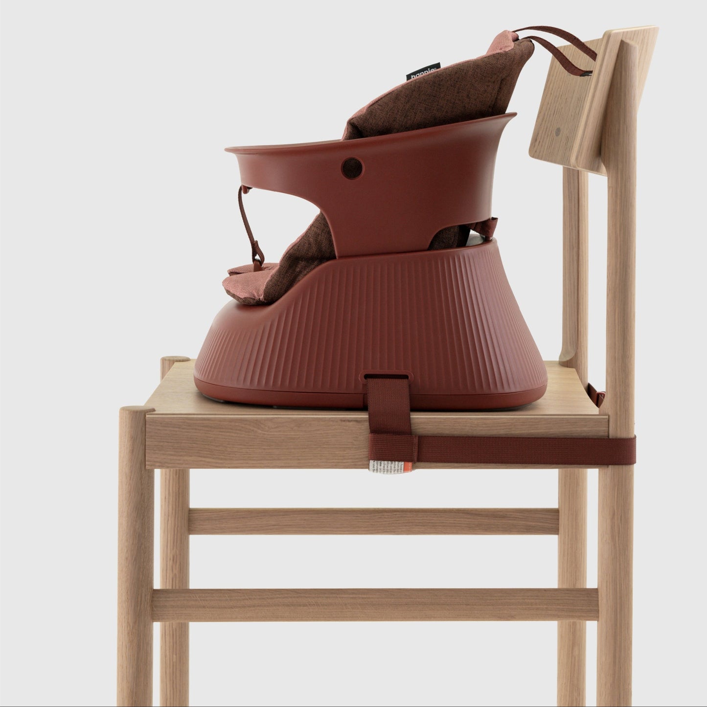 Mahogany Red portable high chair with cushion insert strapped to a wooden chair on a white background. 