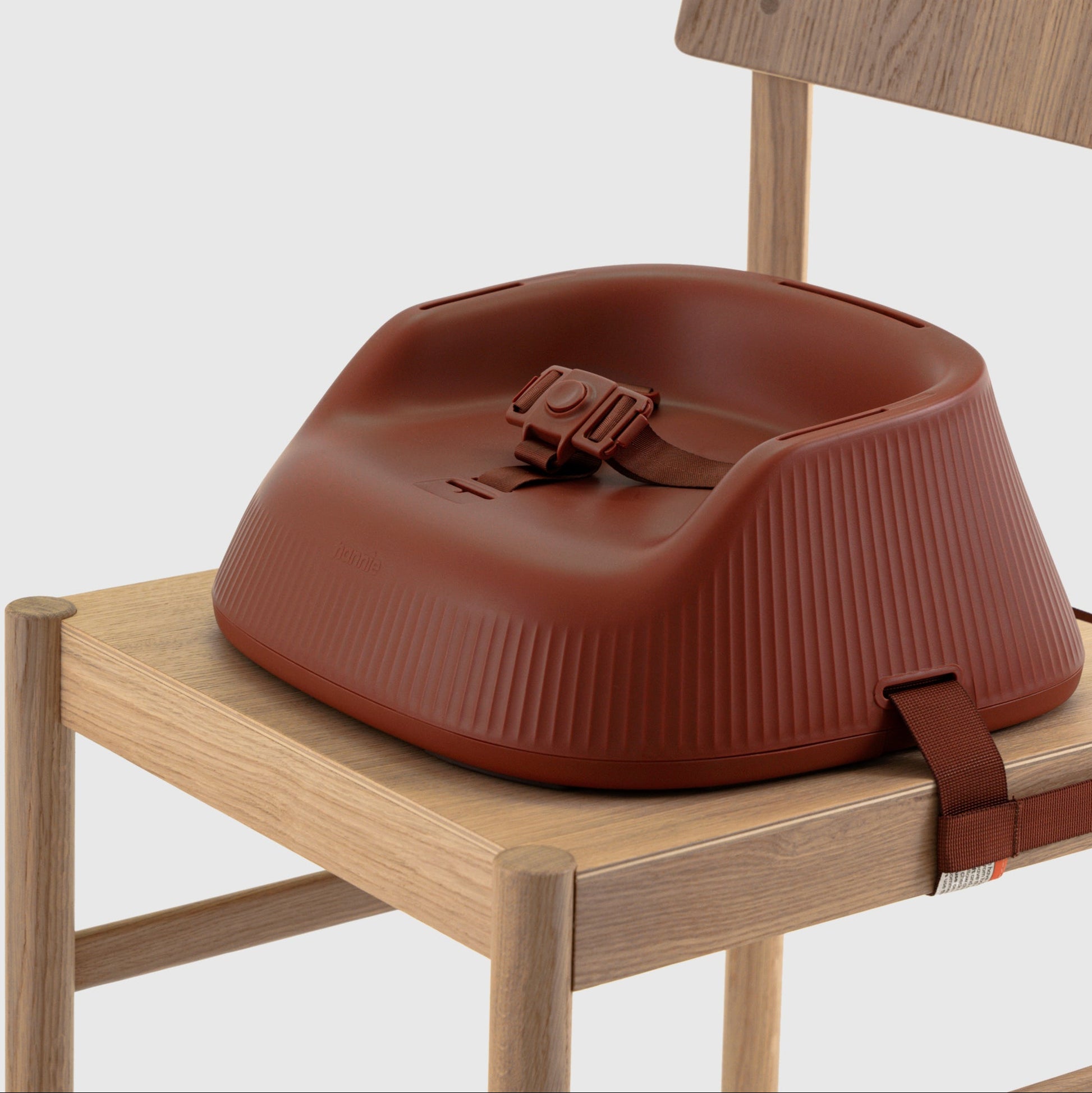 Mahogany Red portable high chair with booster seat with harness strapped to a wooden chair on a white background. 