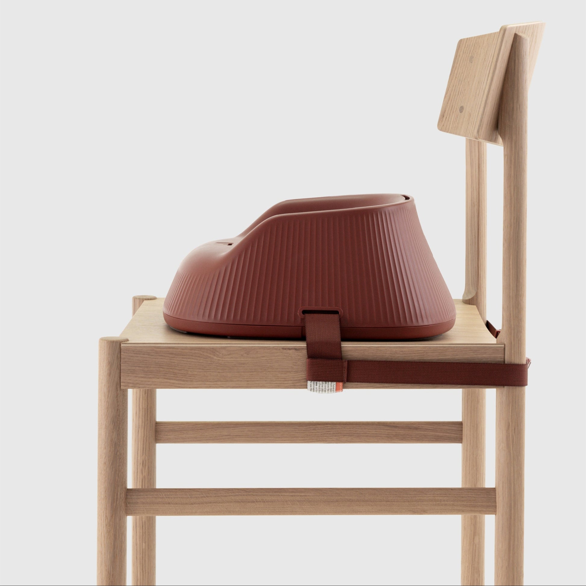 Mahogany Red portable high chair booster seat strapped to a wooden chair on a white background. 
