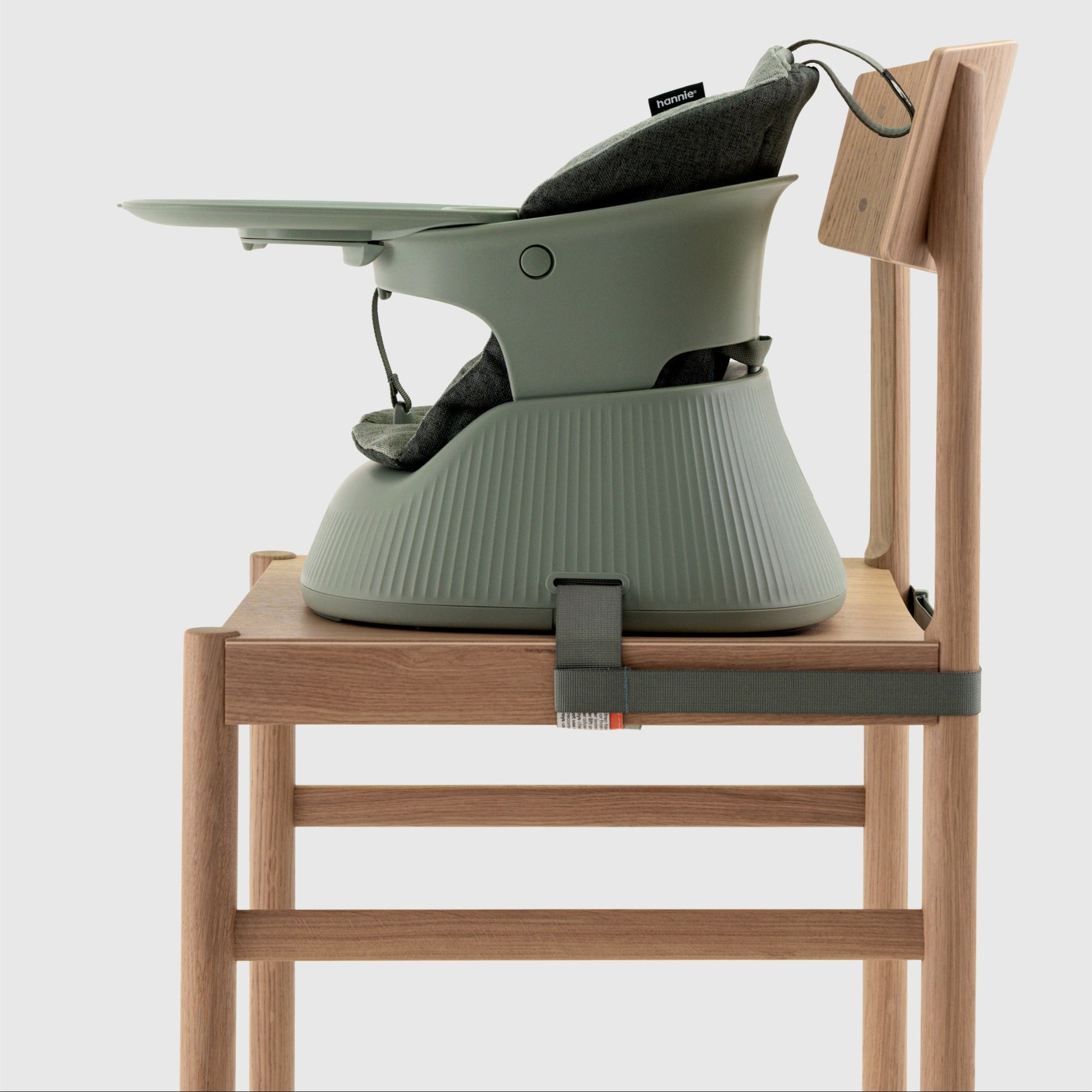 Green baby high chair attached to a wooden chair on a white background