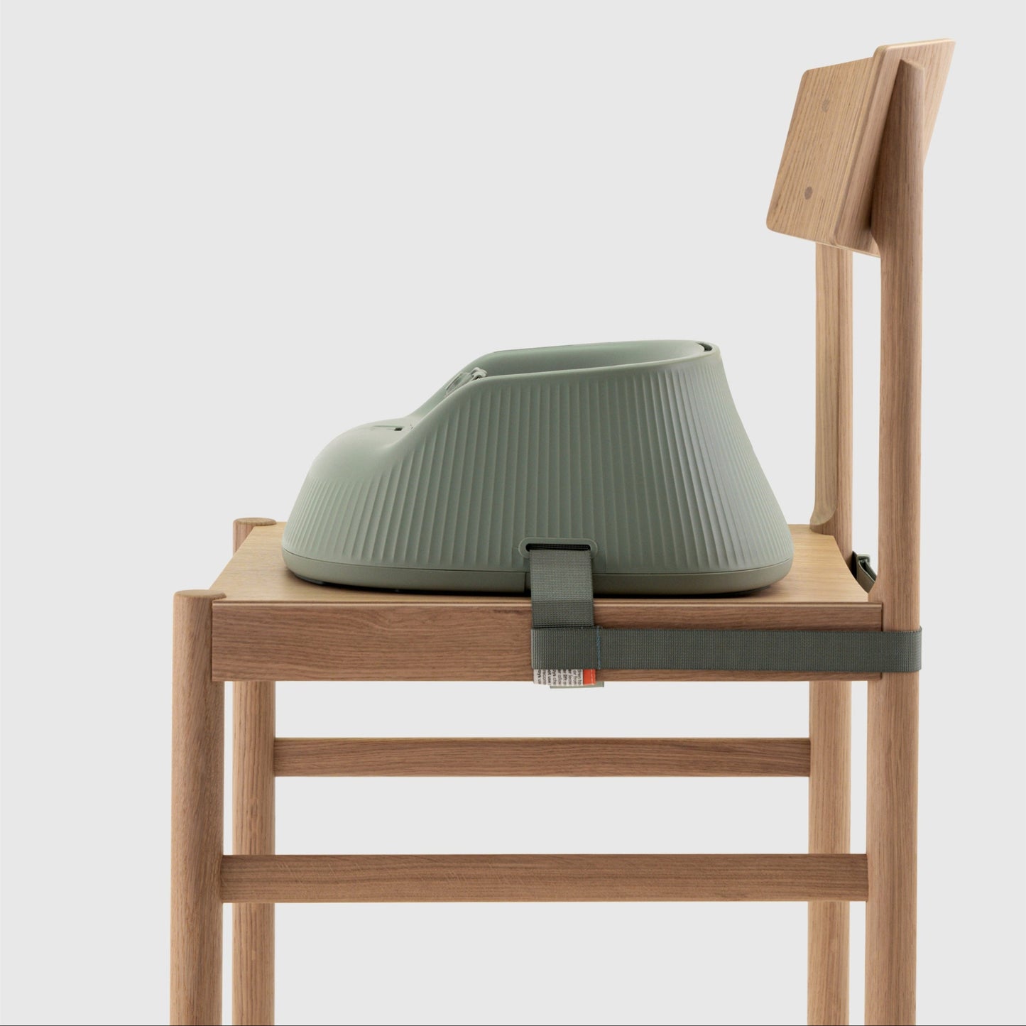 Green baby highchair seat attached to a wooden chair on a white background. 