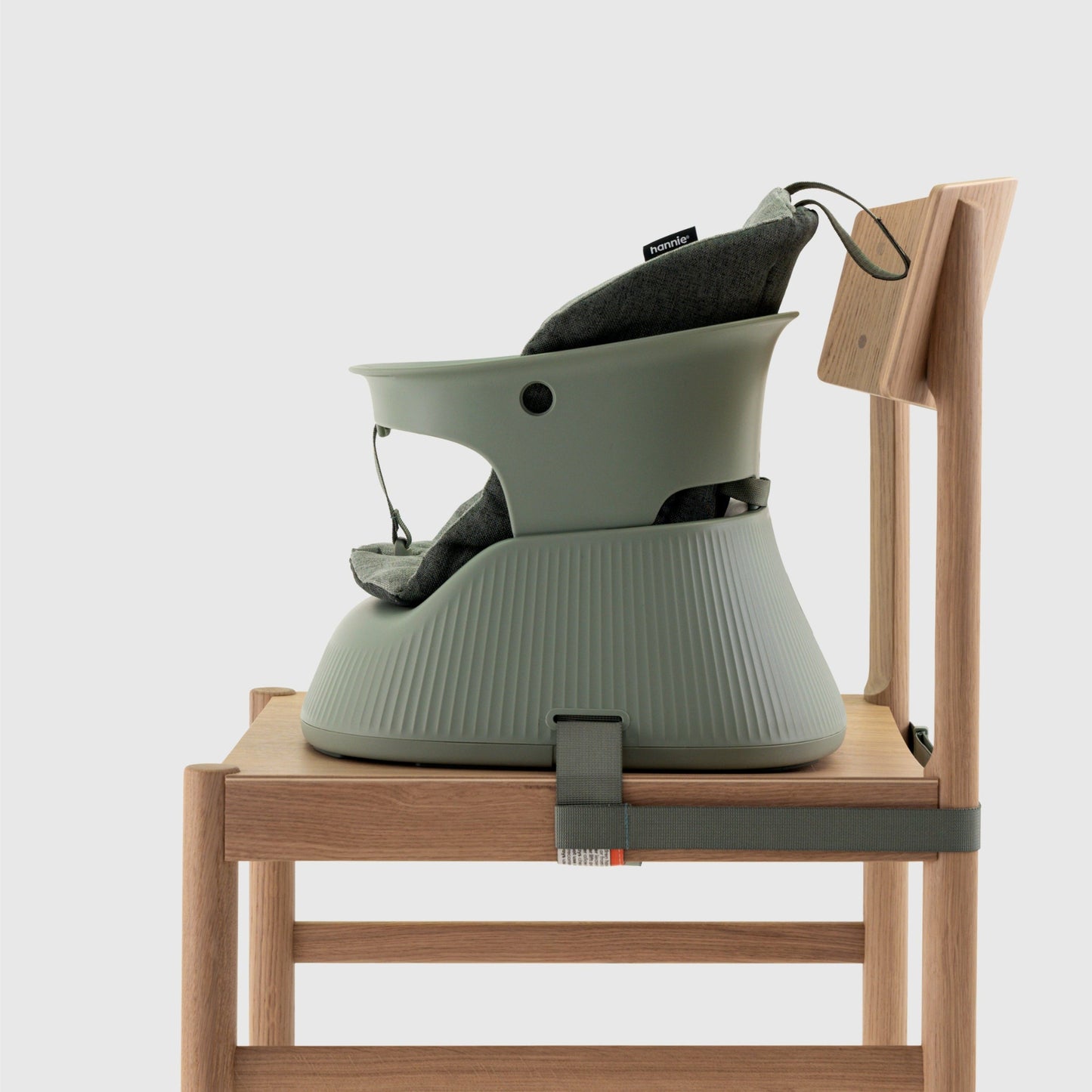 Green baby high chair attached to a wooden stool on a white background