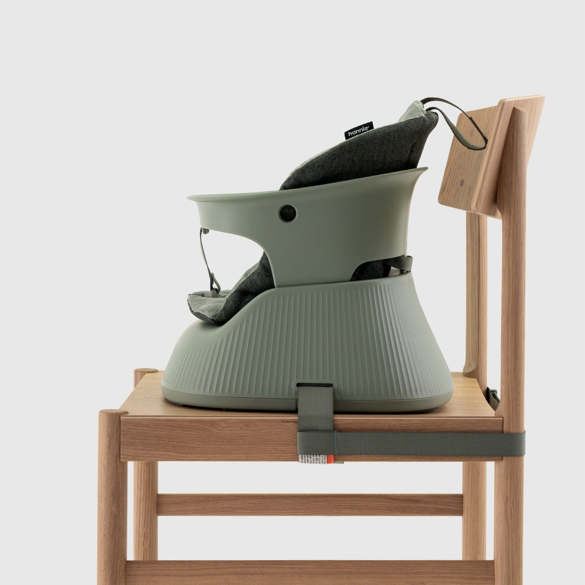 Green baby high chair attached to a wooden stool on a white background
