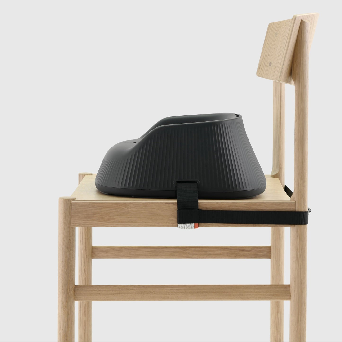 Charcoal Black portable baby booster highchair strapped to a wooden chair on a white background. 