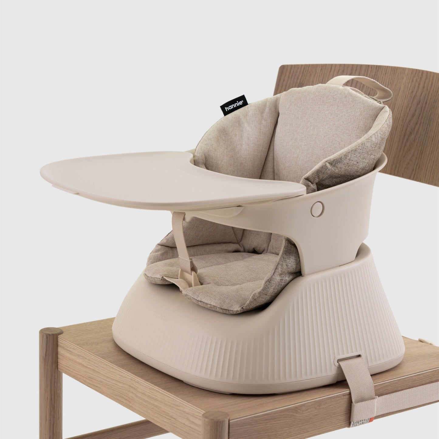 Beige baby high chair on a wooden chair with a white background