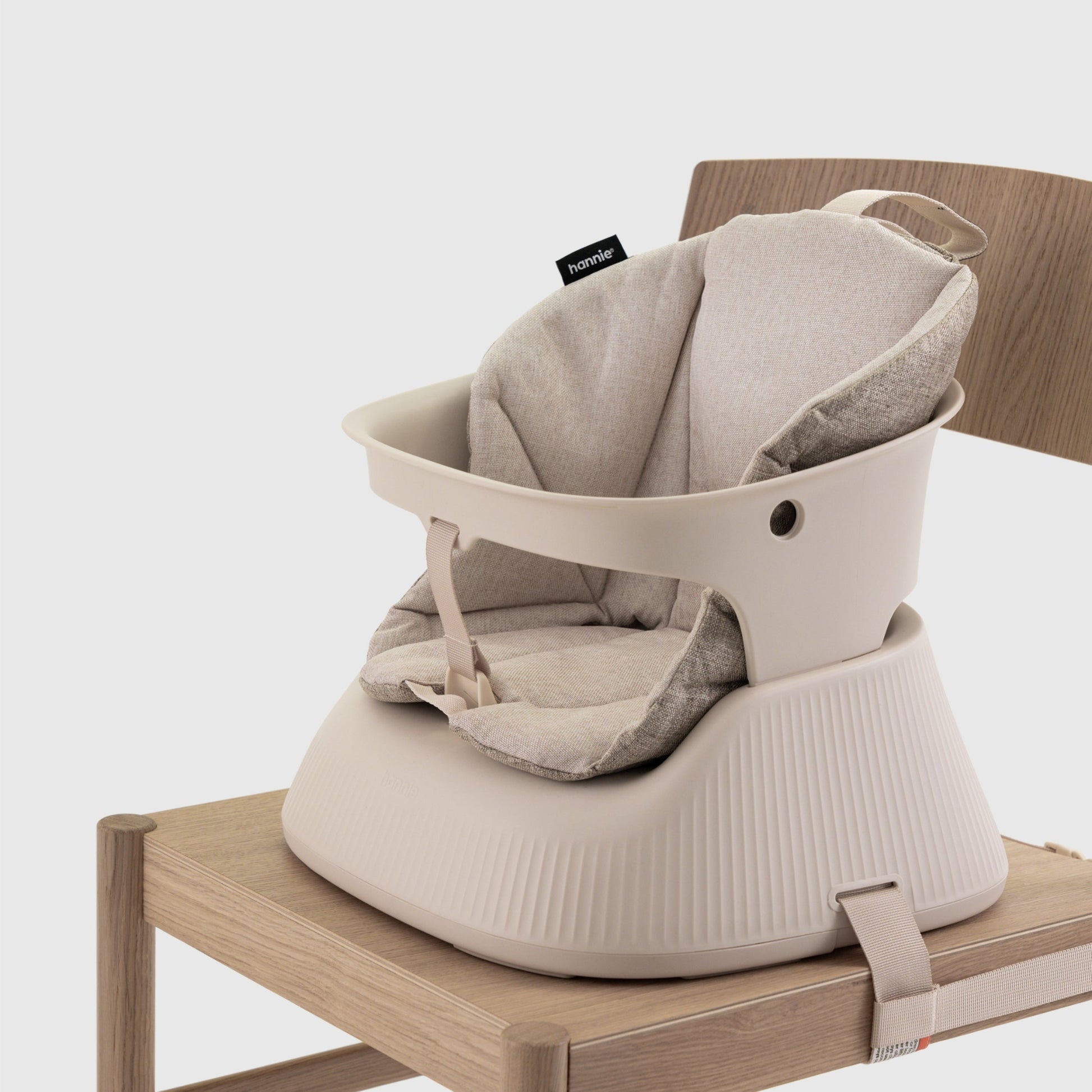 Baby high chair with a beige cushion  attached to a chair on a white background