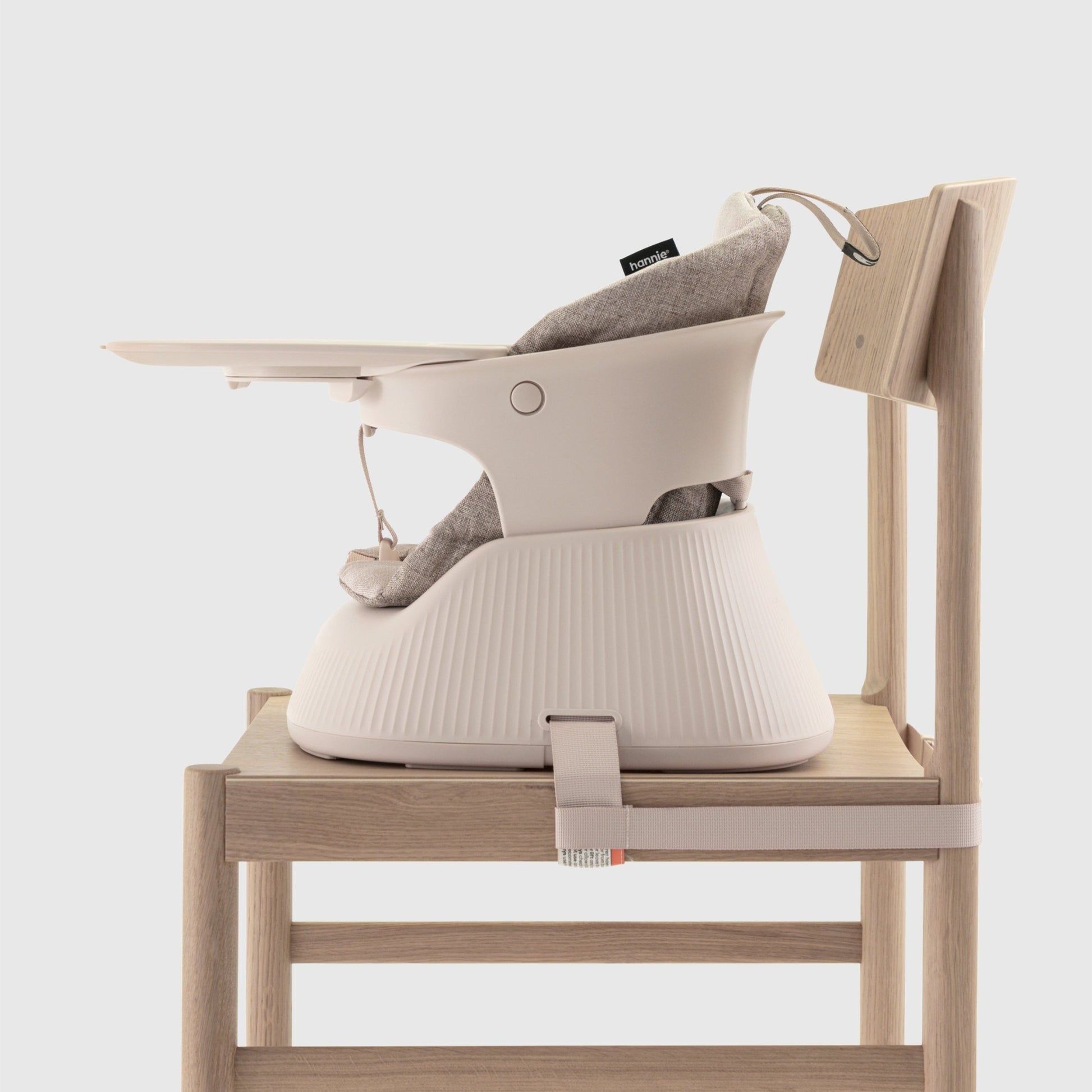 Baby high chair with a beige cushion  and tray attached to a chair on a white background