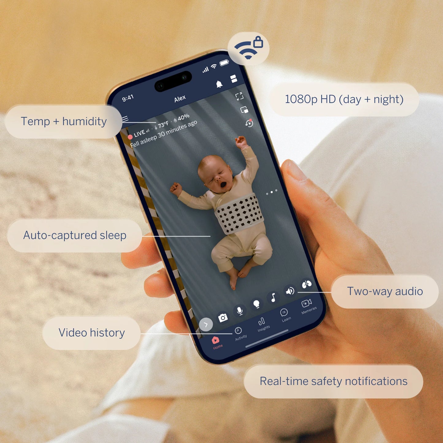 Smartphone displaying a baby monitor app with a baby's video feed, held by a person.