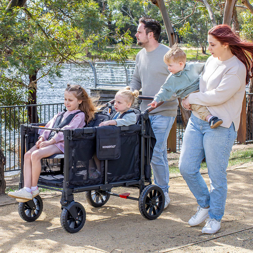 Lifestyle image of a family using the Wonderfold stroller wagon in black out by the river. 